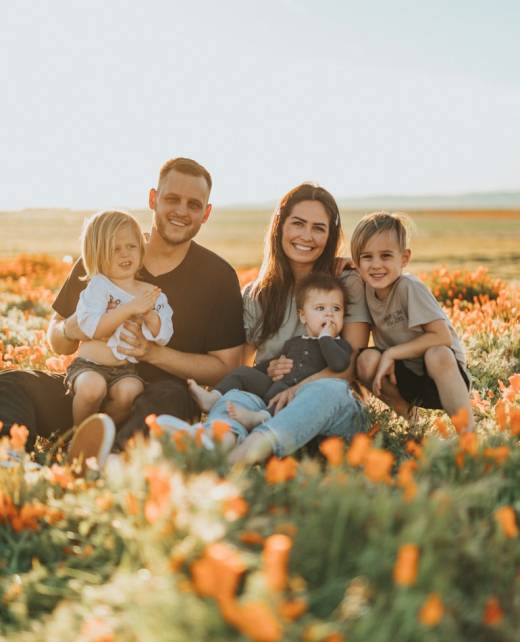 3 women and 2 men sitting on green grass field during daytime